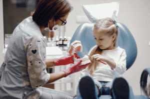 רופאה מראה לילדה קטנה שיניים מדומות