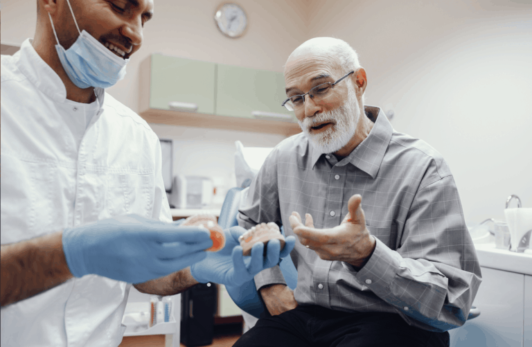 רופא שיניים מראה למטופל שיניים תותבות