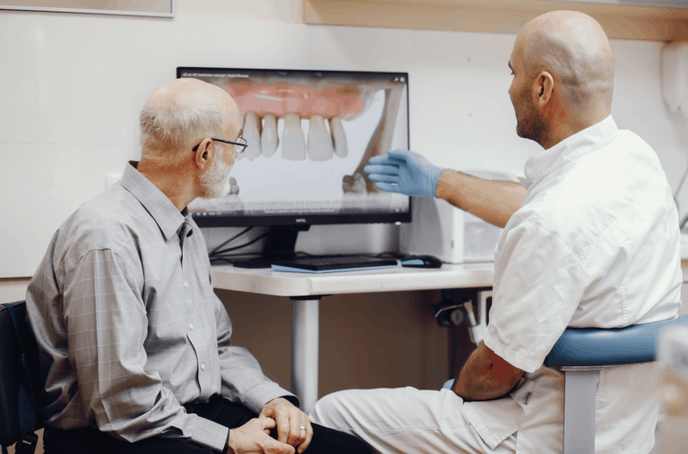 רופא מציג למטופל סוגים שונים של שיניים תותבות